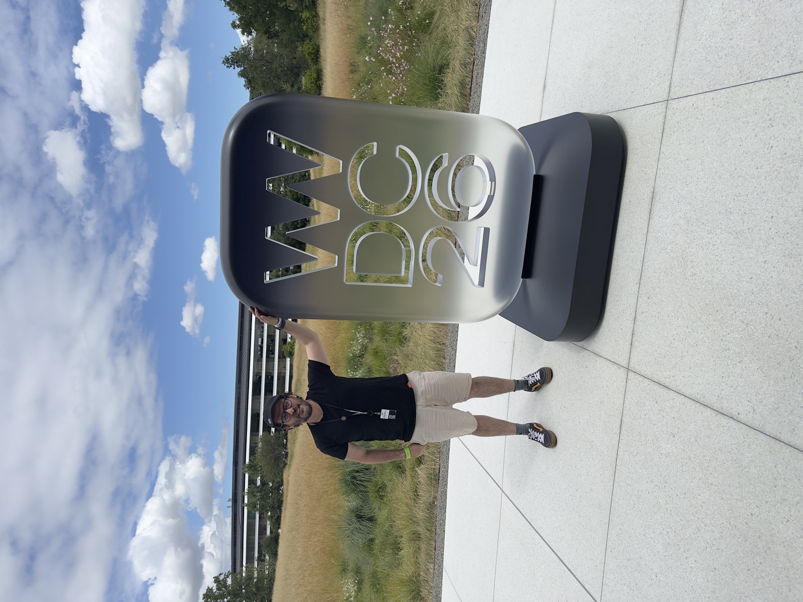 Ezequiel beside the WWDC 26 sign at Apple Park under a cloudy sky